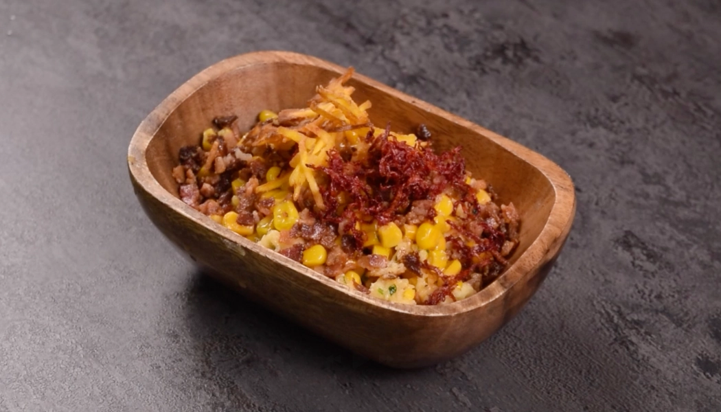 Esquites de maíz con remolacha frita, queso, tocineta y plátano verde